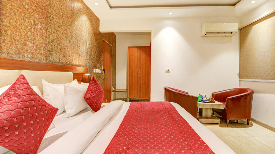 View from the bed looking toward the room entrance and a private seating area with red tub chairs - Hotel Velocity