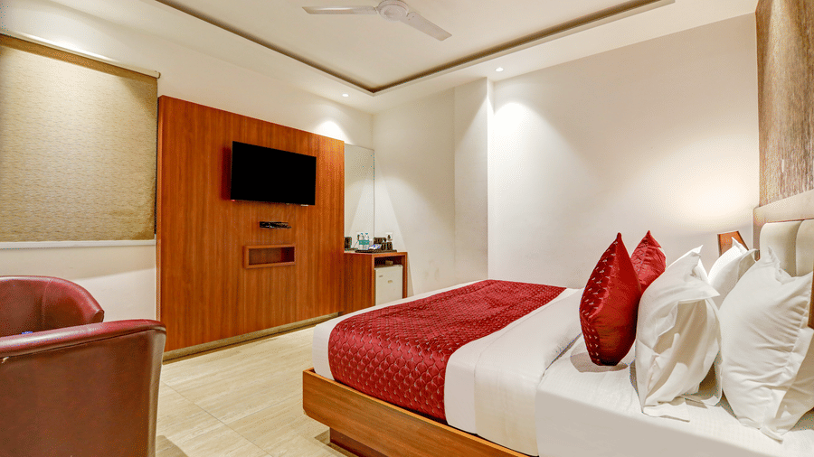Cosy hotel room with a red bed runner, matching pillows, and warm wood wall panelling - Hotel Velocity