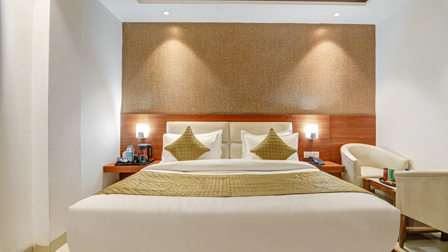Premium hotel room featuring gold bed linens, matching pillows, and a beige feature wall - Hotel Velocity
