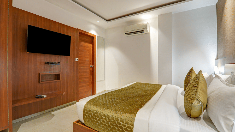 View of the wall-mounted television and integrated wooden wardrobe in a gold-themed room - Hotel Velocity