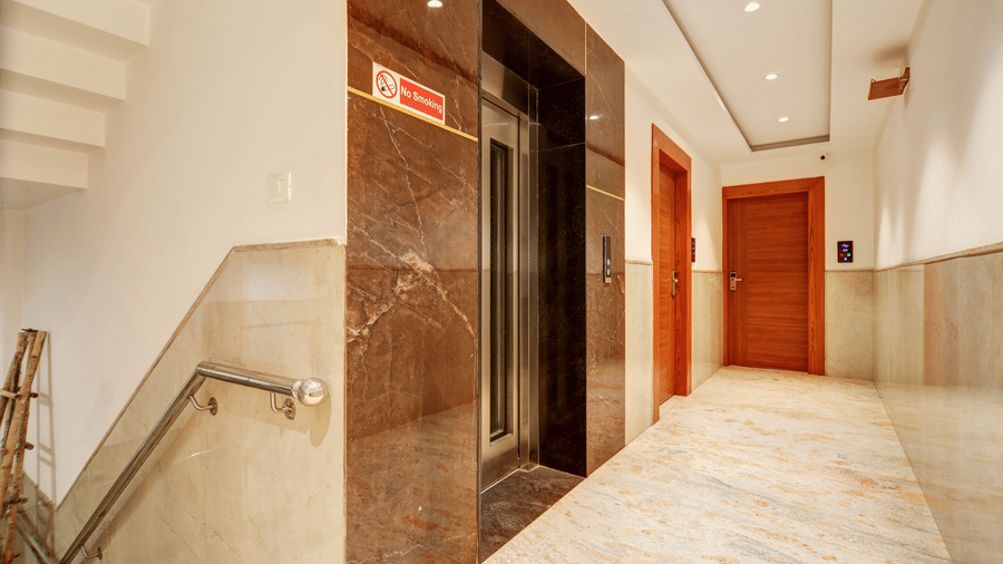 Modern elevator landing and marble staircase area with clean, polished finishes - Hotel Velocity