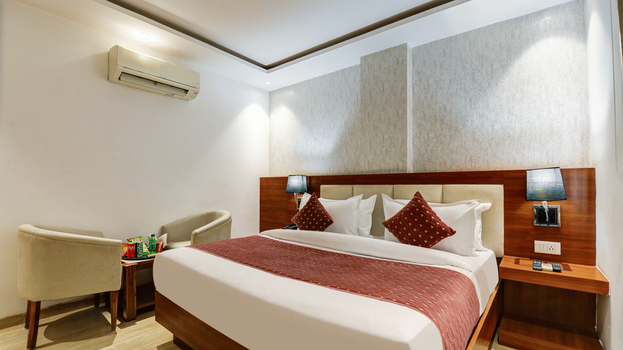 Spacious hotel room setup with two beige armchairs, a side table, and a double bed - Hotel Velocity
