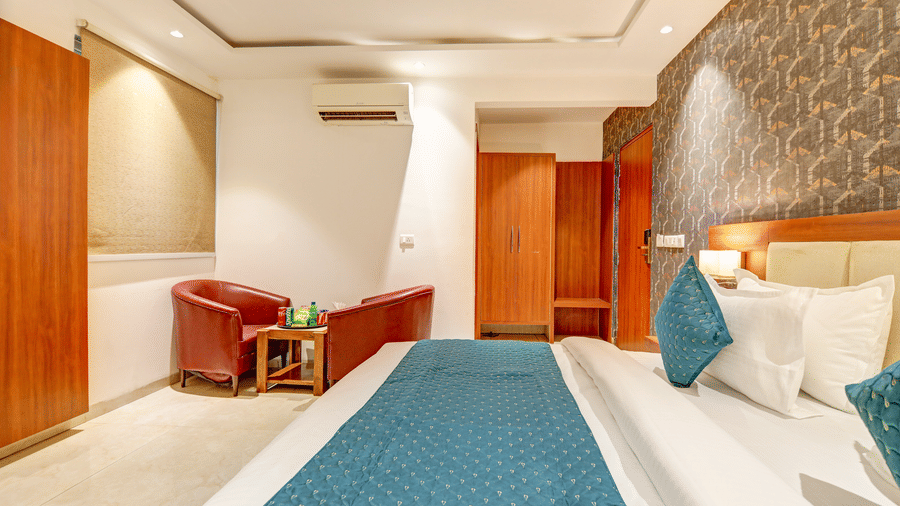 Hotel room interior featuring 2 armchairs, a small coffee table, and a plush bed - Hotel Velocity