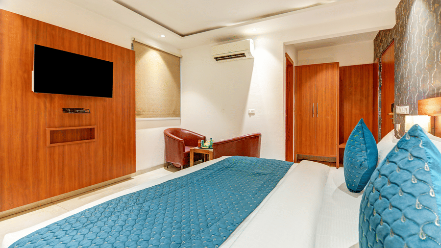 Wide perspective of a hotel room showing a blue quilted bed runner and wall-mounted television - Hotel Velocity