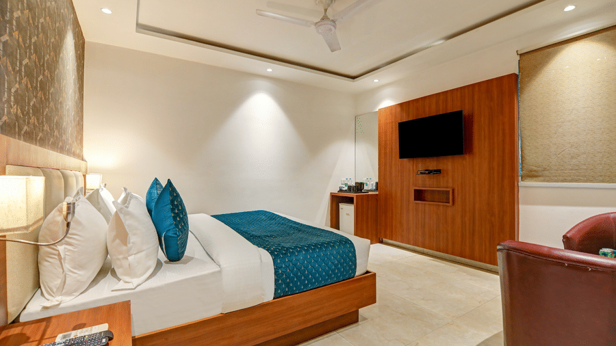Side view of a hotel bed next to a wood-panelled wall and work desk area - Hotel Velocity