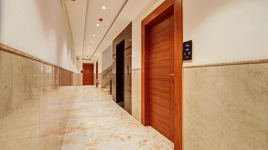 Hallway view showing wooden guest room doors and polished stone walls - Hotel Velocity