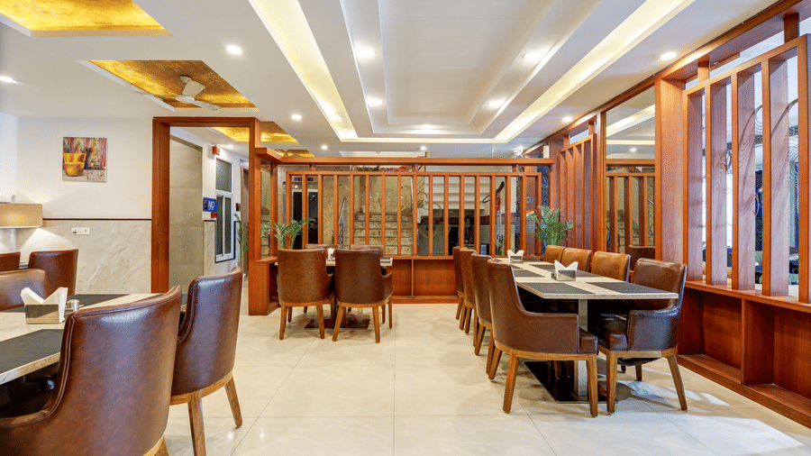 Elegant restaurant dining area with polished wooden furniture and warm ceiling lighting - Hotel Velocity