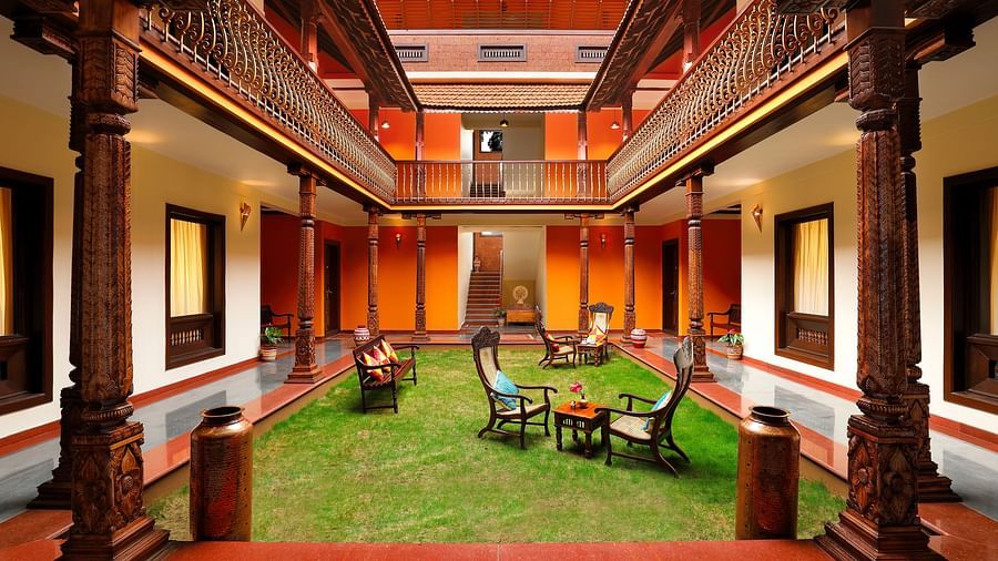 An image of a courtyard in the middle of a property where many table and chairs are kept - Hoysala Village Resort, Hassan