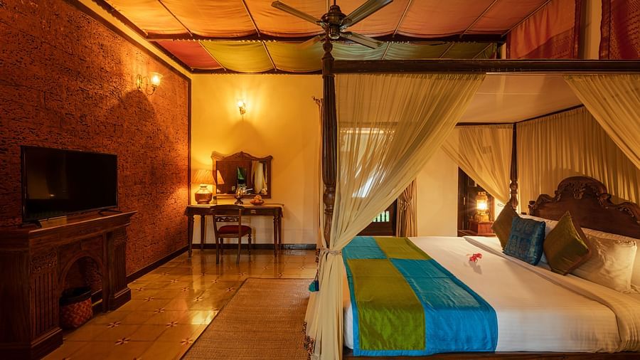 An overview of malnad palace suite with a double bed and tv at hoysala village resort, Hassan.