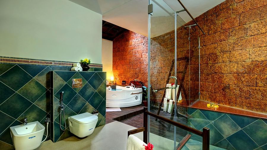 An image of a western style bathroom with showerheads, glass, fauctes, buckets, and other functionalities - Hoysala Village Resort, Hassan
