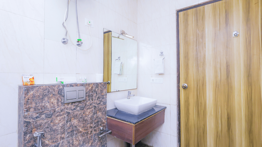 A hotel bathroom with a modern sink, mirror, and a simple, functional design - Hyphen Business Hotel, Noida