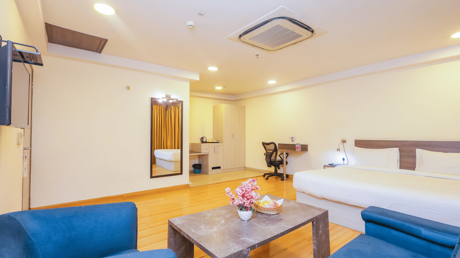 An expansive hotel room featuring a large bed, a comfortable seating area, and a television - Hyphen Business Hotel, Noida
