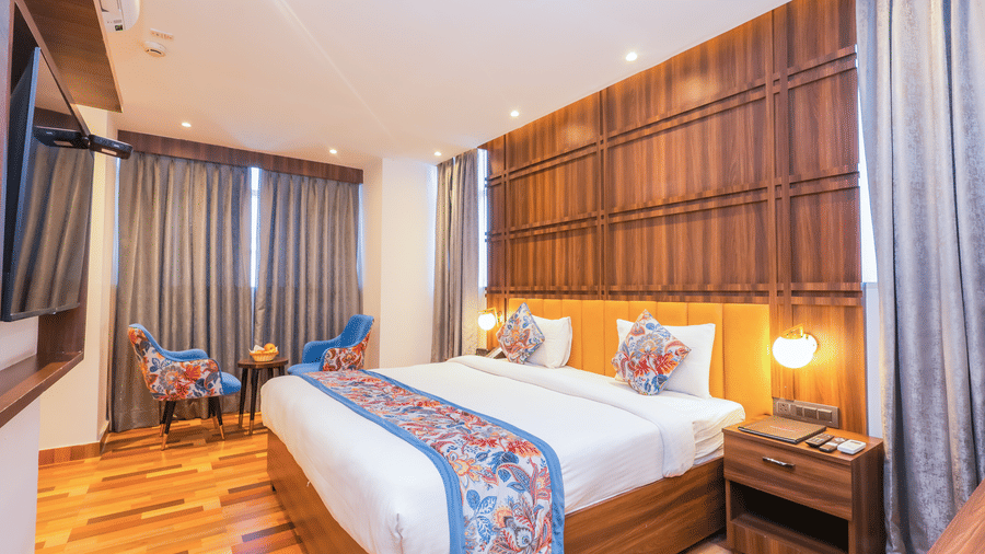 View of a luxurious hotel room with a spacious bed, wooden accents, and a tranquil ambience - Hyphen Business Hotel, Noida