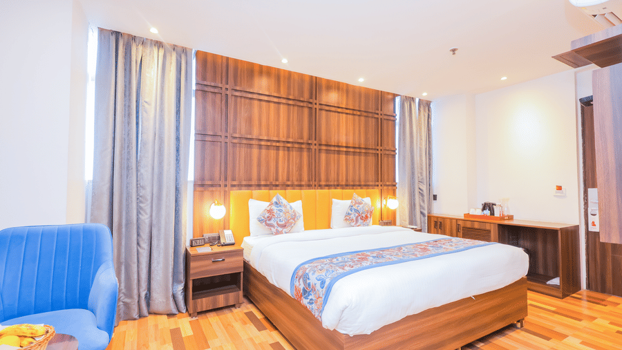 A comfortable hotel room with a large bed, wooden feature wall, and warm lighting - Hyphen Business Hotel, Noida