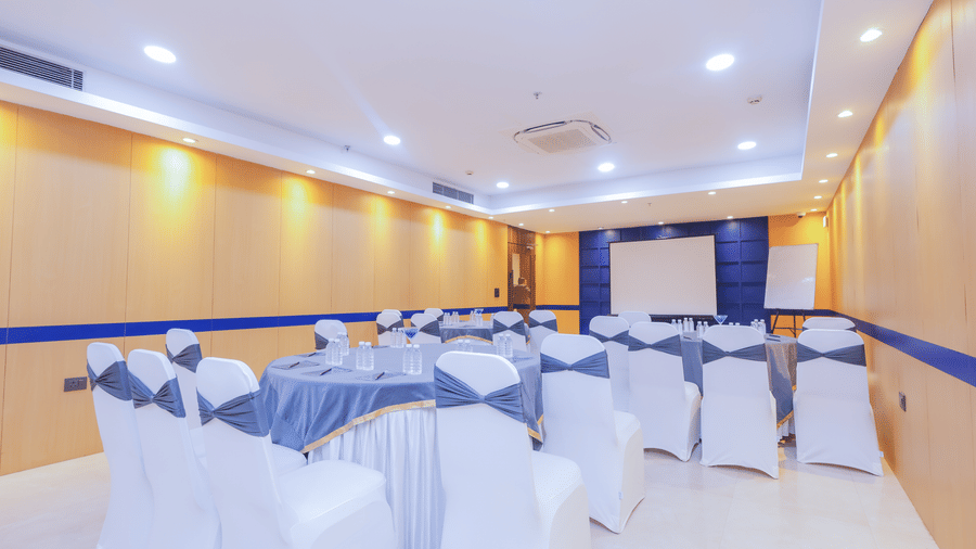A wide shot of a versatile event space set up with multiple round tables and chairs - Hyphen Business Hotel, Noida