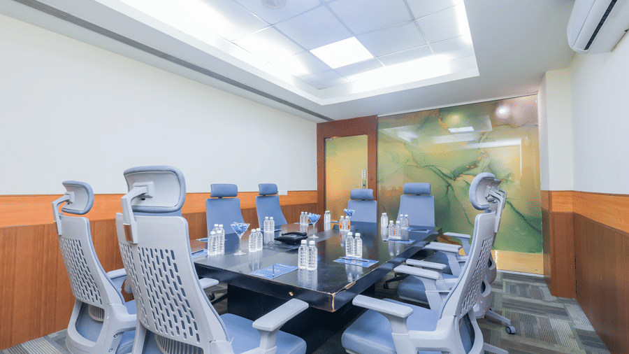 A spacious conference room with a large table and grey office chairs, suitable for corporate gatherings - Hyphen Business Hotel, Noida