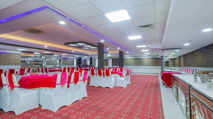 An event space or banquet hall with red carpet, tables set for dining, and bright lighting - Hyphen Business Hotel, Noida