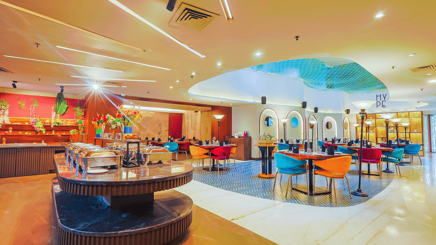 A wide view of the hotel restaurant showing its modern decor and diverse seating arrangements - Hyphen Business Hotel, Noida