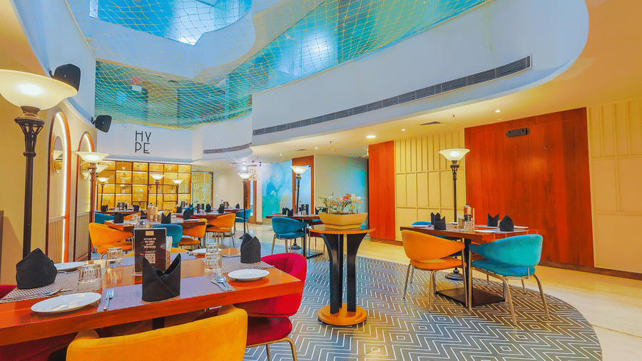 A brightly lit restaurant interior with a mix of colourful seating and elegant design - Hyphen Business Hotel, Noida
