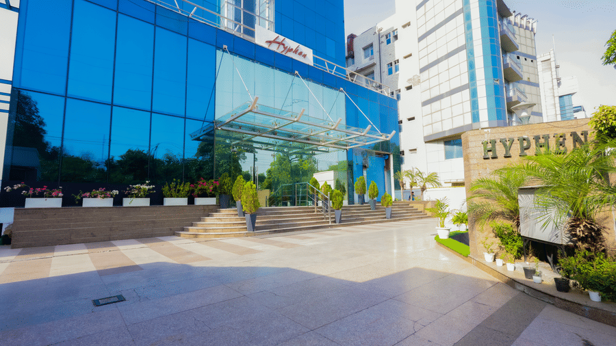 The exterior of a modern building with a glass facade, showcasing the Hyphen Business Hotel signage - Hyphen Business Hotel, Noida