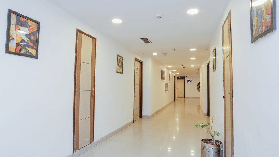 A hotel room with a double bed, floral patterned wallpaper, and a bedside table with a lamp - Hyphen Grand, Haridwar