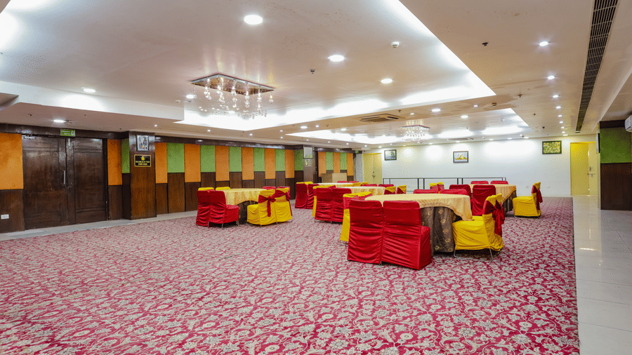 A wide view of a banquet hall set for an event with red and yellow decor - Hyphen Grand, Haridwar