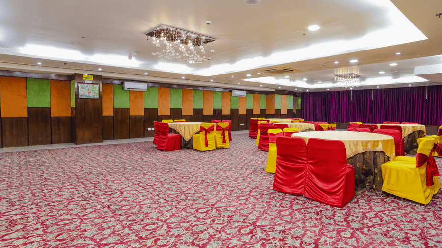 A conference or event room with red carpet and tables covered in red and yellow cloths - Hyphen Grand, Haridwar