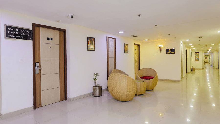 Another perspective of a hotel room with a double bed, floral wallpaper, and a sitting area - Hyphen Grand, Haridwar