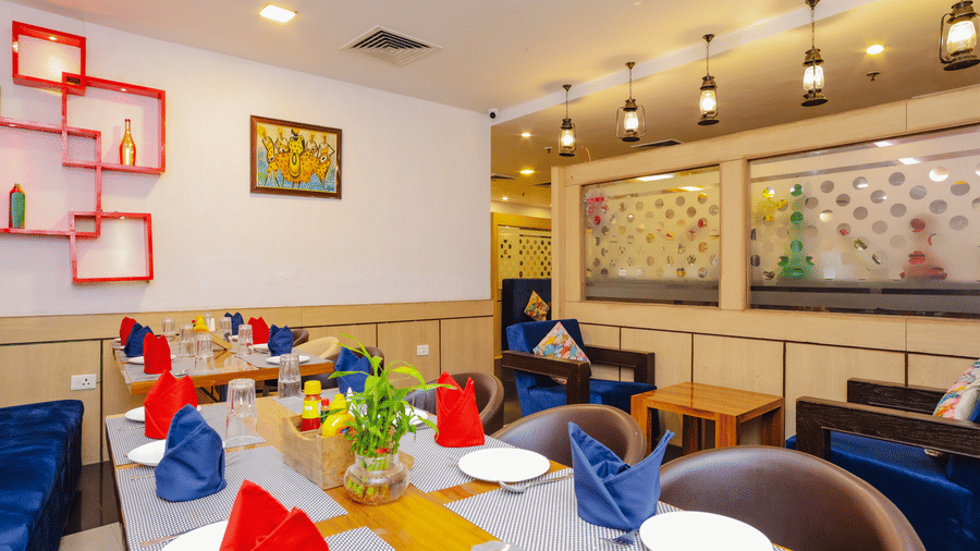 A modern restaurant interior with a colourful table setting and stylish decor - Hyphen Grand, Haridwar