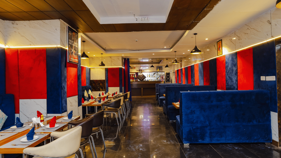 A contemporary restaurant space with blue booth seating and elegant lighting - Hyphen Grand, Haridwar