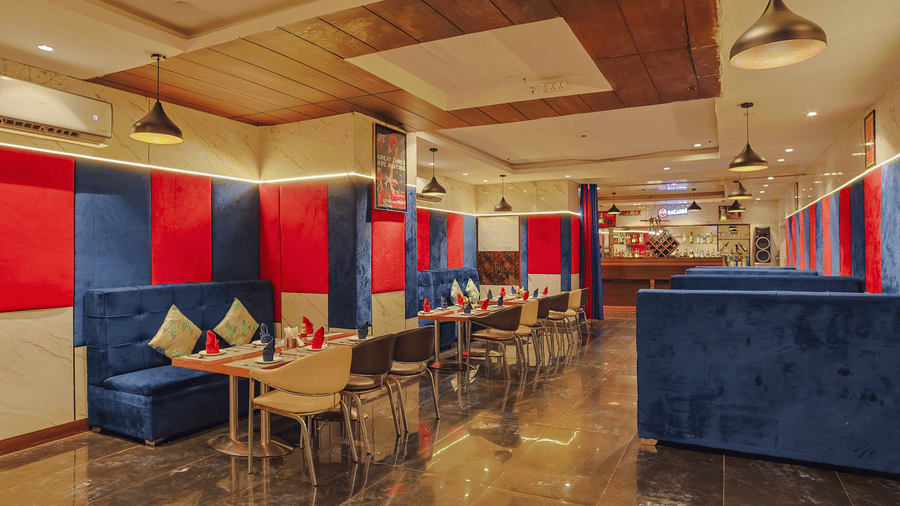 A stylish restaurant dining area with blue and red seating booths and tables - Hyphen Grand, Haridwar