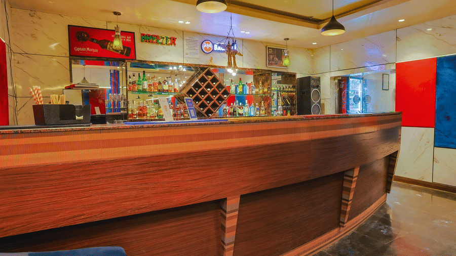 The reception or bar area of a hotel restaurant with a wooden counter and subtle lighting - Hyphen Grand, Haridwar