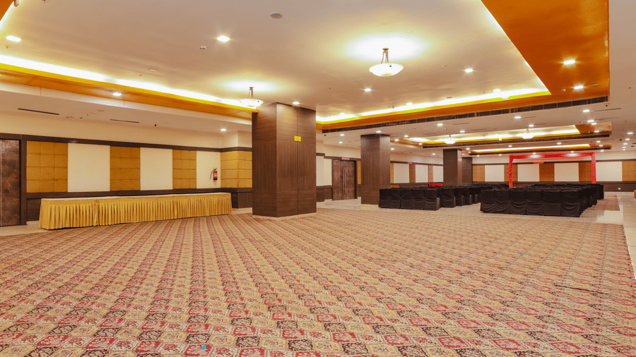 An empty banquet hall with red patterned carpet and warm lighting - Hyphen Grand, Haridwar