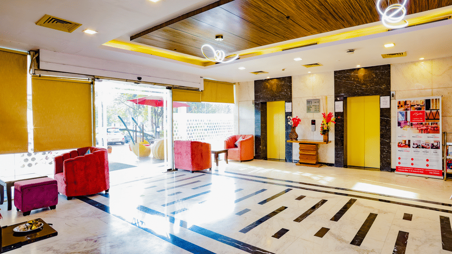 A clean and simple hotel corridor with light coloured walls and dark wooden doors - Hyphen Grand, Haridwar