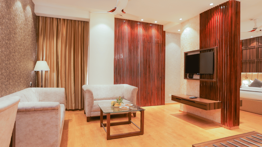 Modern suite with seating area, flat-screen TV, and warm lighting at Hyphen Premier Hotel, Meerut.