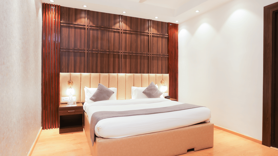 Comfortable king size bed with elegant wood paneLling and ambient lighting in a premium room at Hyphen Premier Hotel, Meerut.