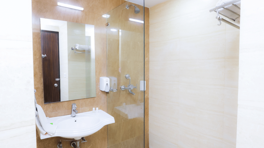Clean and compact bathroom with glass shower enclosure, modern sink, and elegant design at Hyphen Premier Hotel, Meerut.