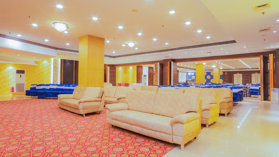 Banquet hall with sofa seating area and pillars in between with ambient lighting at Hyphen Premier Hotel, Meerut.