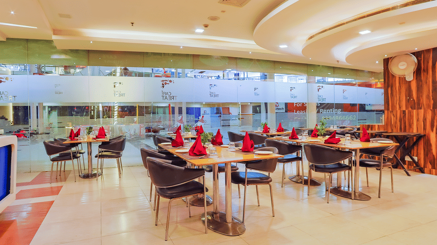 Spacious restaurant with curved ceiling design and modern decor at Cafe Treat - Hyphen Premier Hotel, Meerut.