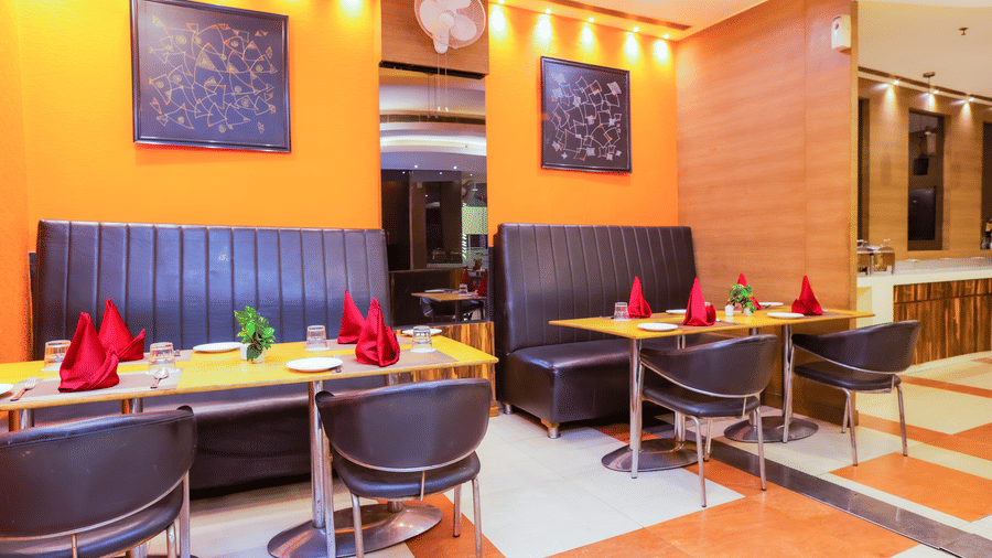 Restaurant seating with warm tones and cosy lighting at Hyphen Premier Hotel, Meerut.