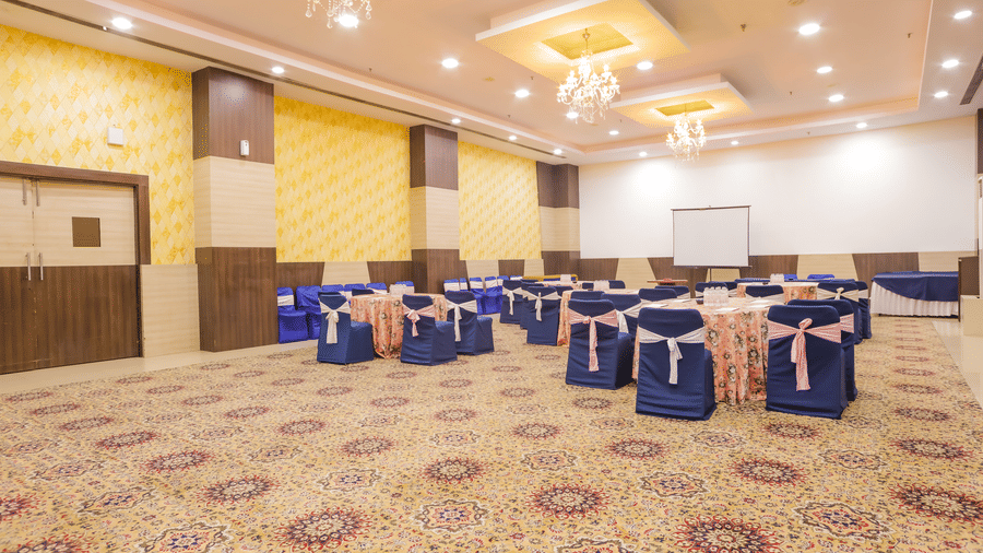 Spacious banquet hall with cluster seating arrangement and patterned carpet flooring at Hyphen Premier Hotel, Meerut..