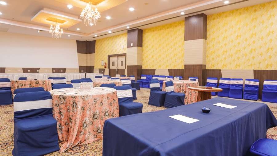 Conference hall with cluster seating arrangement and navy blue covers at Hyphen Premier Hotel, Meerut.