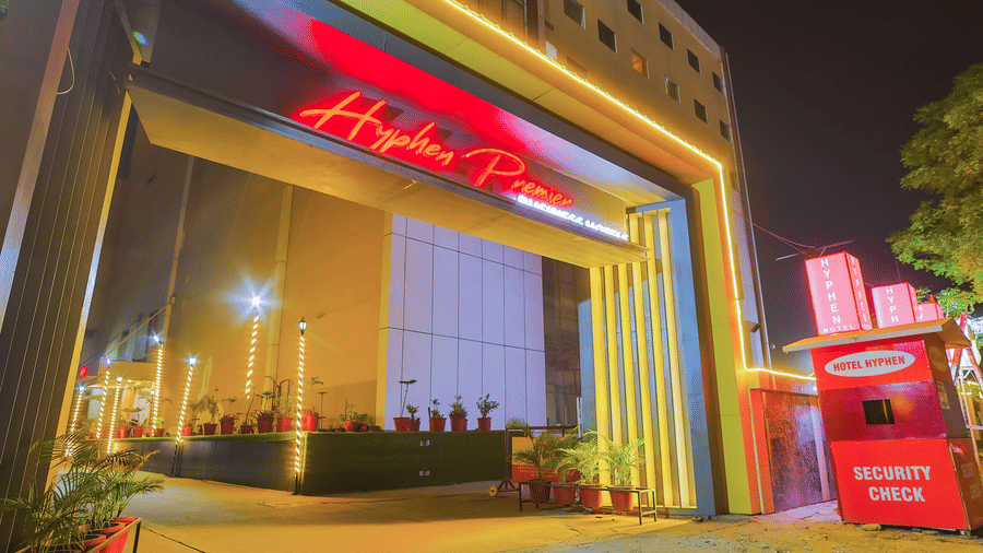 Facade entrance of Hyphen Premier Hotel, Meerut with a cabin room besides in red colour.