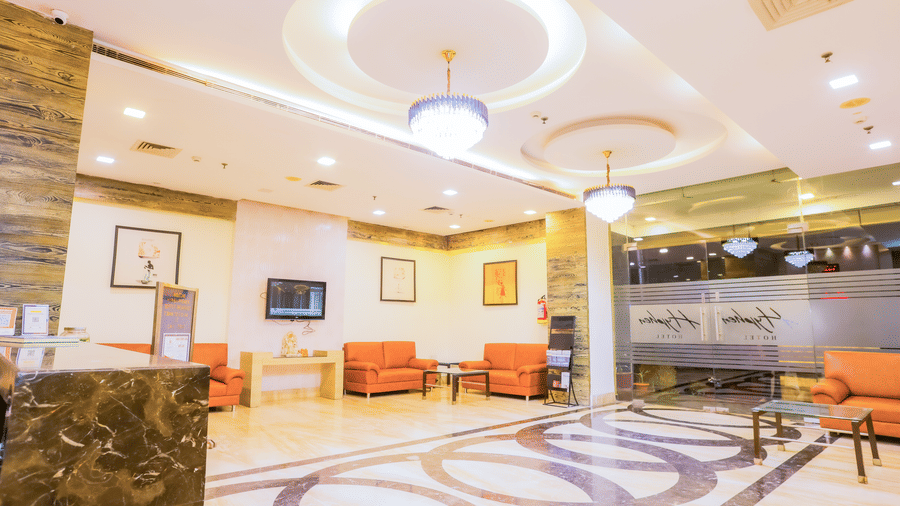 Spacious lobby area with sofa seating area, coffee table, and a reception desk at Hyphen Premier Hotel, Meerut. 