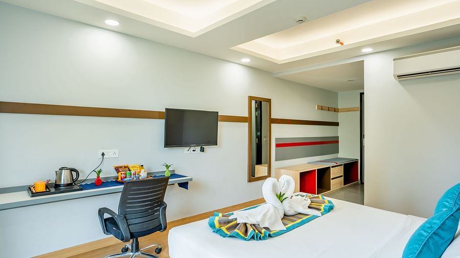 An image of a room where a chair there is a chair, a table, and a flat TV screen | Inde Hotel Golf Course Extension