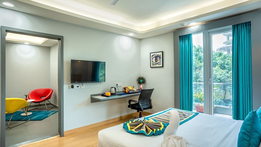 An image of a large bedroom with table, chair, and an adjacent sitting room | Inde Hotel Golf Course Extension