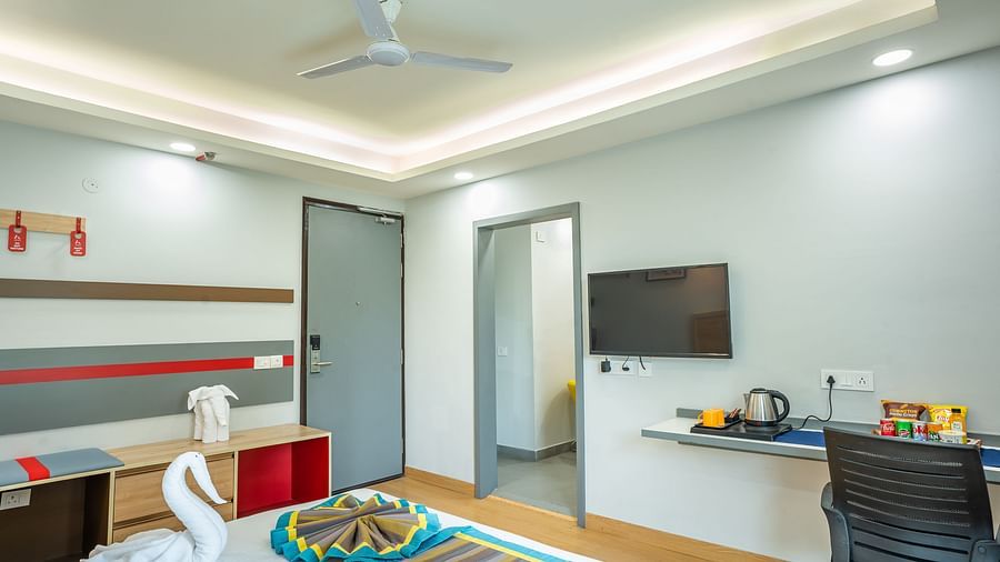 An image of a bedroom with chair, table, and a TV | Inde Hotel Golf Course Extension