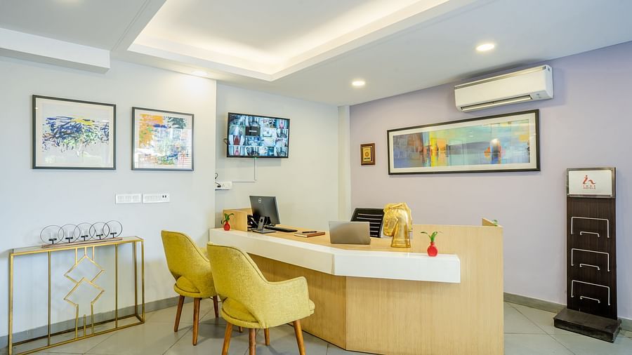 An image of a reception of the hotel where a desk and two chairs are placed | Inde Hotel Golf Course Extension