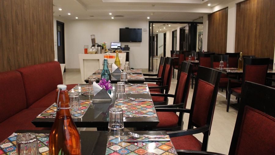 An image of a dining table with several chairs in a dining hall at Inde Hotels Vista Voods Gurgaon