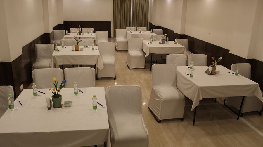 An image of a banquet hall at Inde Hotel Vista Woods featuring a few sets of tables with four chairs each